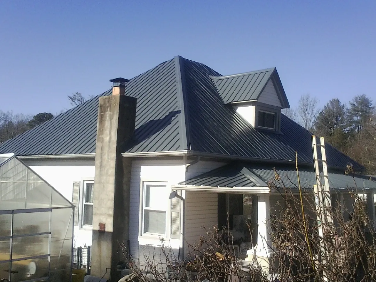 Dark blue standing seam metal roof on a white farmhouse with dormer — Slate & Tile Roof Repair by Roofing Brothers in Garibaldi