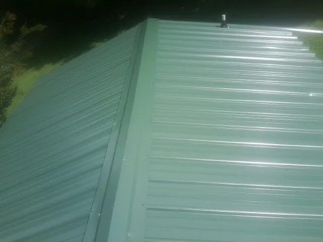 New green metal panels meeting at the ridge of a roof — Flat Roof Repair work by our crew in Garibaldi