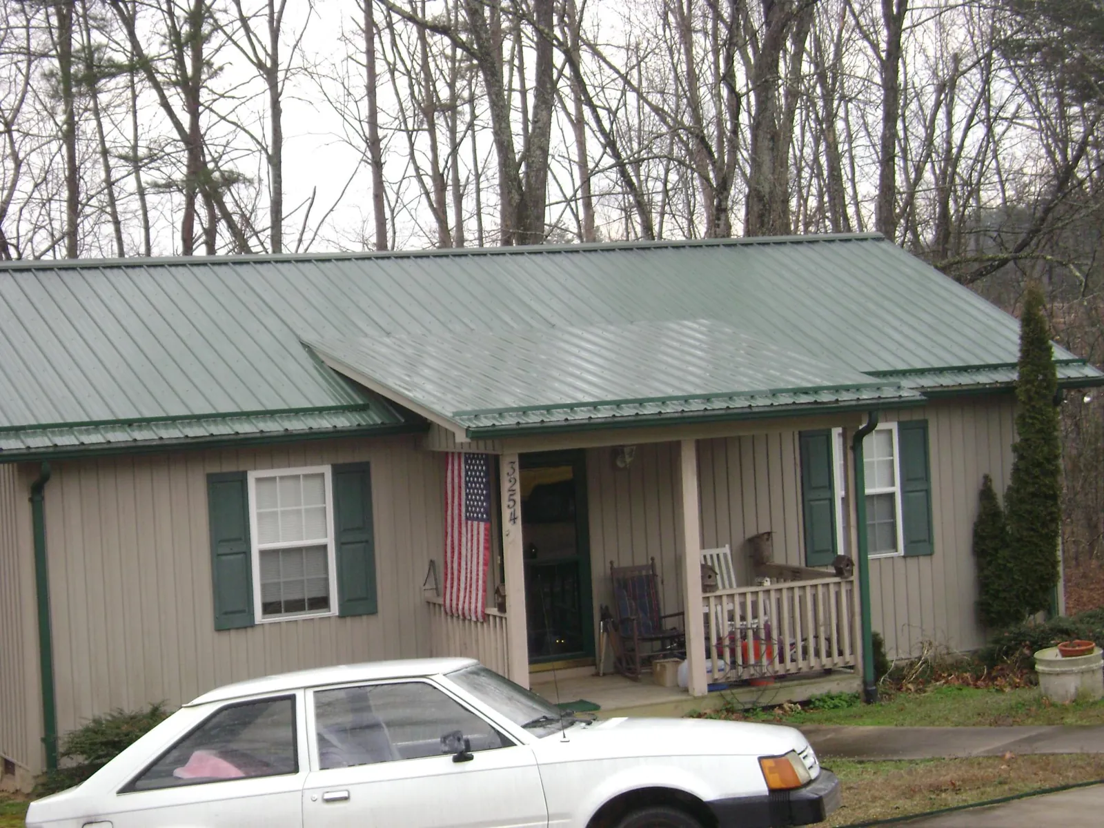 Green metal roof and front porch on a tan sided cottage in Garibaldi