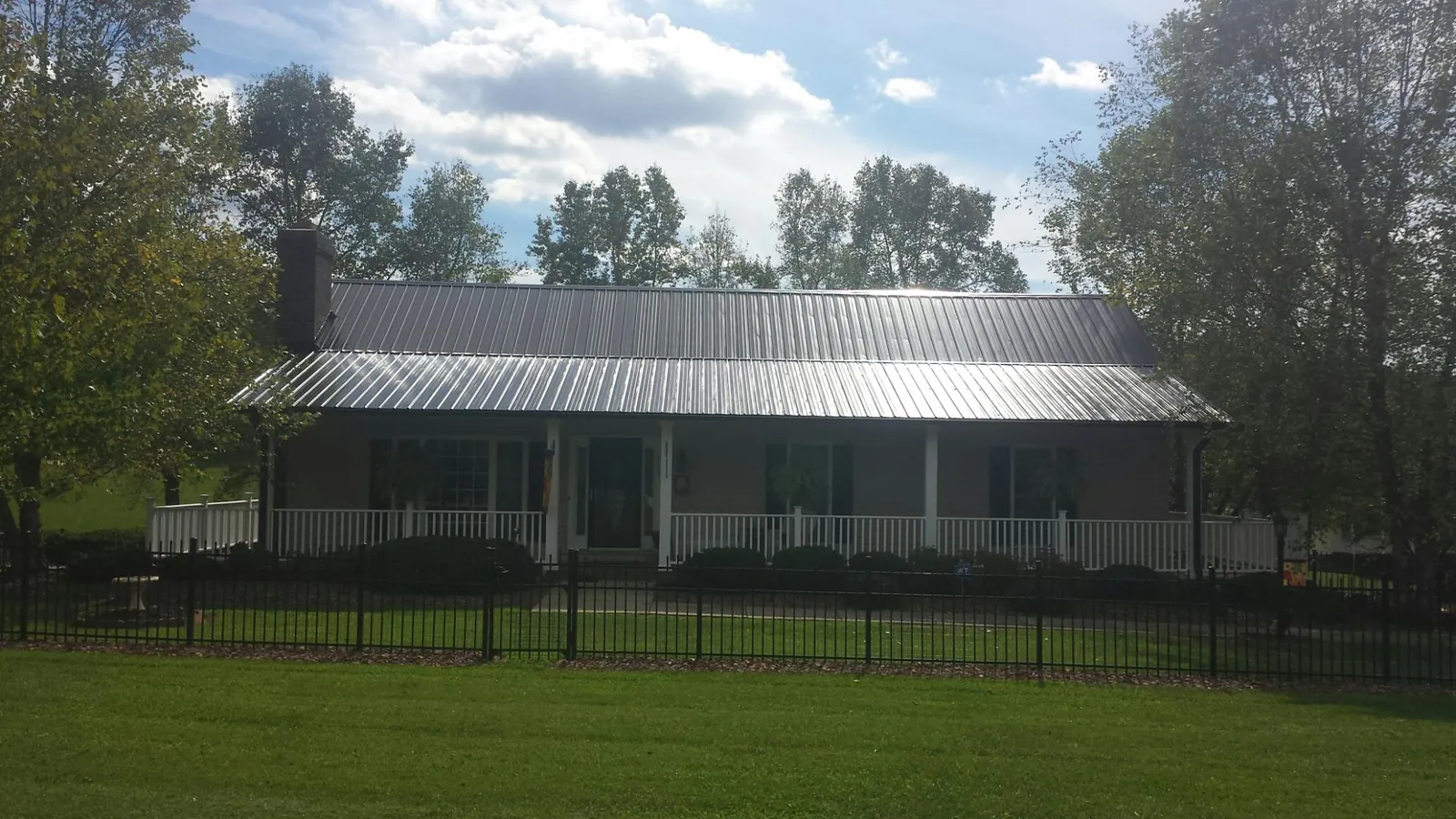 Gray metal roof on a brick ranch with a full width front porch — Gutter Guard Installation work by our crew in Garibaldi