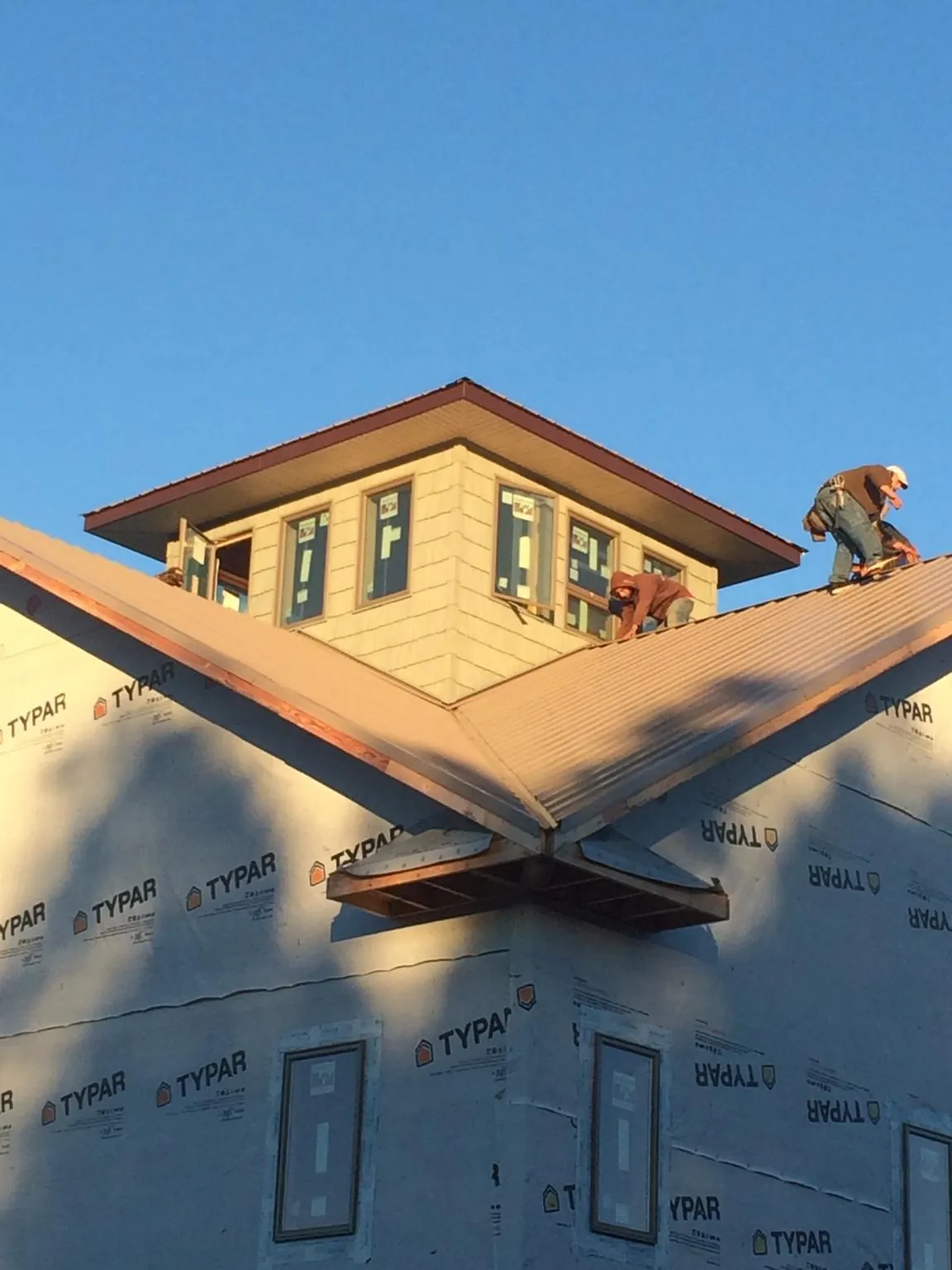 Roofers working around a rooftop cupola on a new metal roof at sunset — Roof Waterproofing in Garibaldi by Roofing Brothers